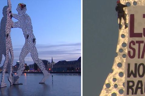 Aktivisten klettern auf dem Molecule Man in Berlin herum und bringen ein Transparent an