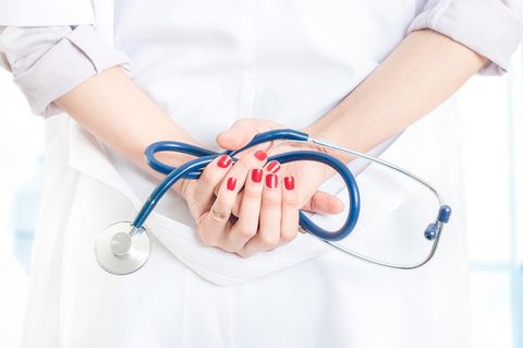 Eine Ärztin hält ein Stethoskop hinter ihrem Rücken
