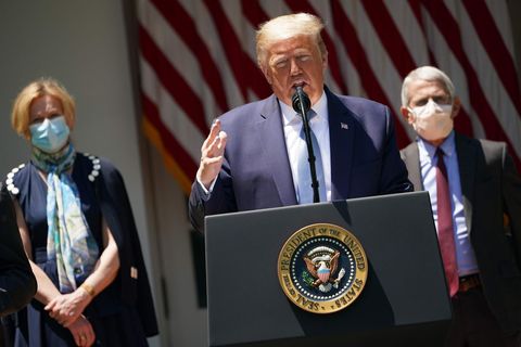 US-Präsident Donald Trump bei einer Rede, hinter ihm steht sein maskierter Gesundheitsexperte Anthony Fauci