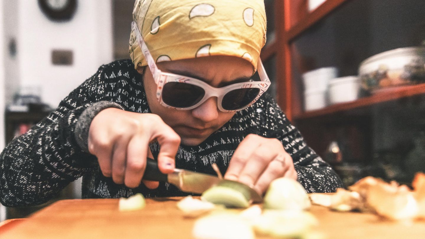 Ein Kind schneidet Zwiebeln mit Kopftuch und Brille auf