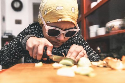 Ein Kind schneidet Zwiebeln mit Kopftuch und Brille auf