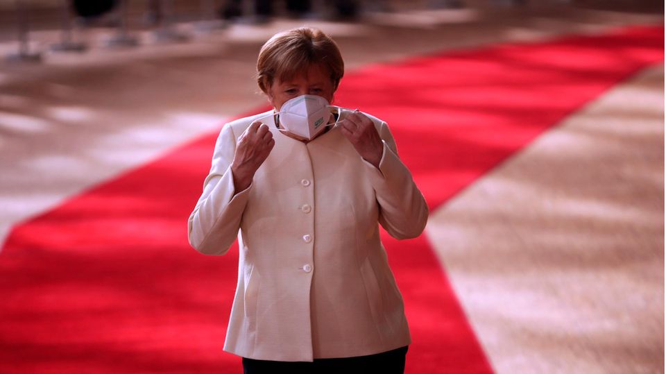 Angela Merkel setzt sich am Sonntag Morgen beim EU-Gipfel eine Maske auf.