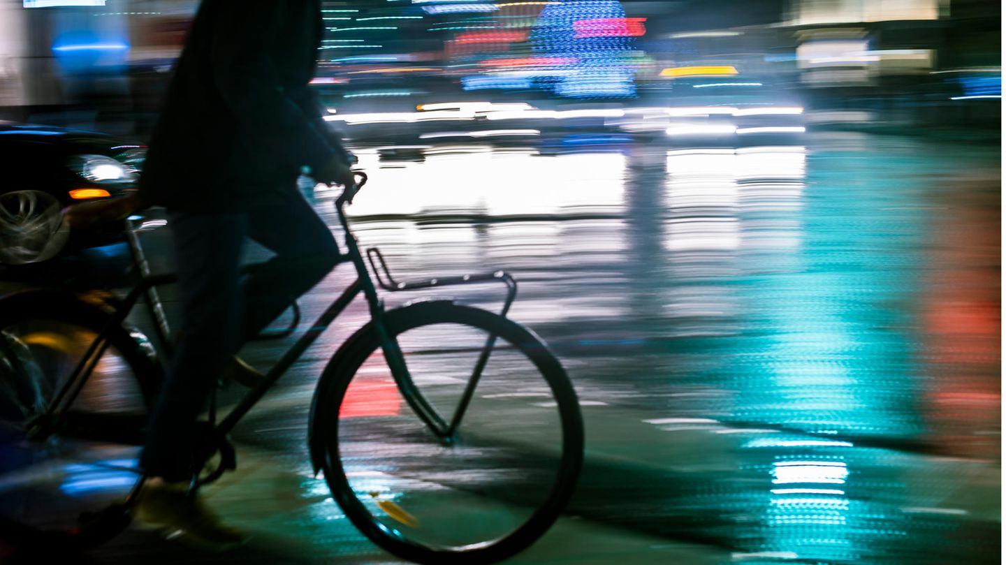 Ein Mann fährt nachts auf einem Fahrrad durch die Stadt