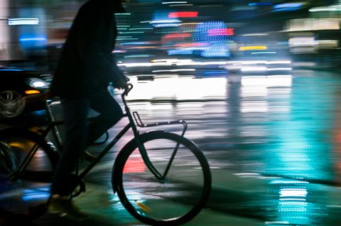 Ein Mann fährt nachts auf einem Fahrrad durch die Stadt