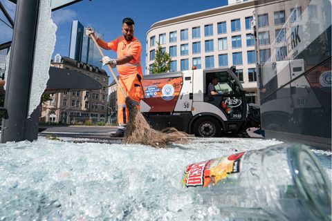 Mitarbeiter der Stadtreinigung beseitigen am Morgen vor der Alten Oper Scherben der zertrümmerten Scheiben einer Bushaltestelle