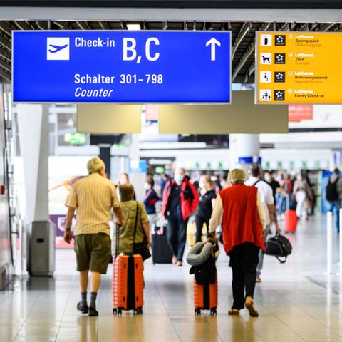Reisende gehen am Flughafen Frankfurt mit Gepäck durch die Abflughalle im Terminal 1