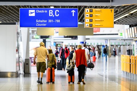 Reisende gehen am Flughafen Frankfurt mit Gepäck durch die Abflughalle im Terminal 1