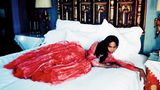 Naomi Campbell liegt im Ballkleid auf einem Hotelbett