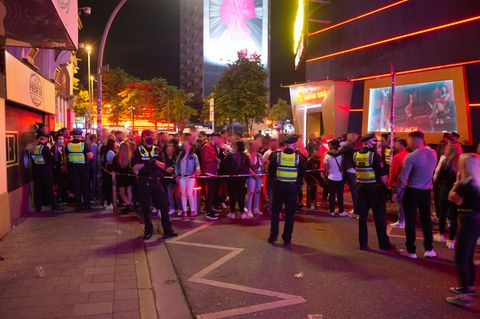 Dutzende Menschen stehen dicht beieinander an dem von der Polizei gesperrten Eingang zur Großen Freiheit