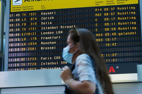 Berlin: Vor der Ankunfts-Anzeigetafel geht eine Reisende mit Mundschutz durch den Flughafen Tegel