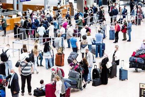 Flugpassagiere mit Mund-Nasen-Schutzmasken stehen an Check-in Schaltern des Flughafens Hamburg