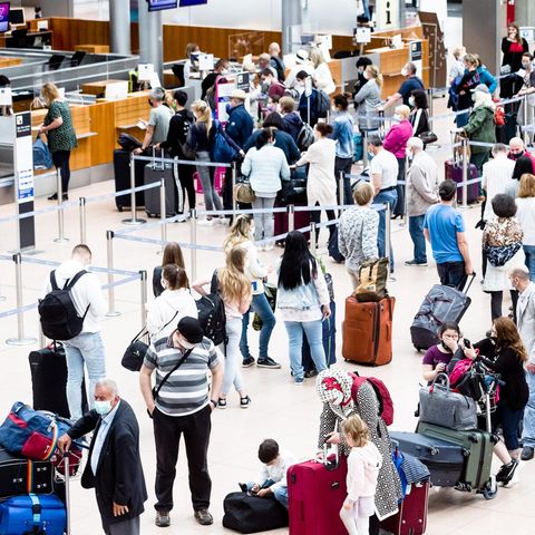 Flugpassagiere mit Mund-Nasen-Schutzmasken stehen an Check-in Schaltern des Flughafens Hamburg