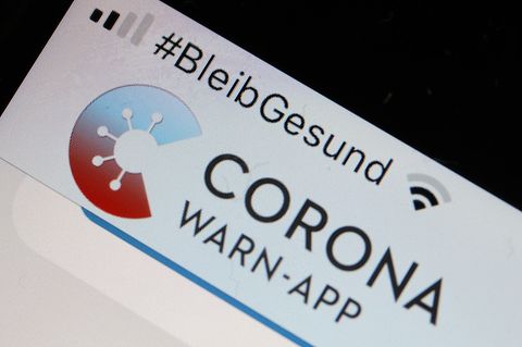 Die Corona-Warn-App mit der Seite zur Risiko-Ermittlung ist im Display eines Smartphone zu sehen