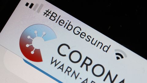 Die Corona-Warn-App mit der Seite zur Risiko-Ermittlung ist im Display eines Smartphone zu sehen