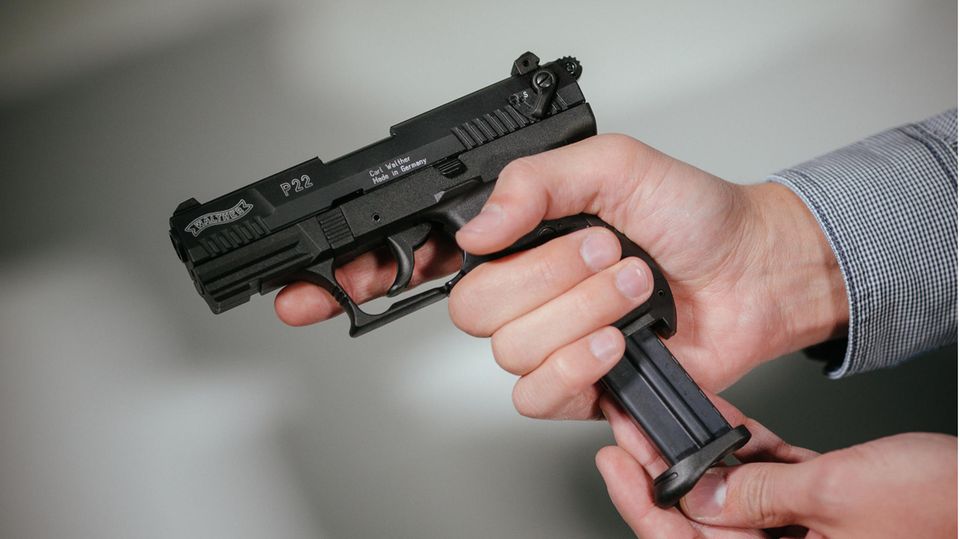 Hände laden eine Schreckschuss-Pistole "Walther P22" mit einem Magazin