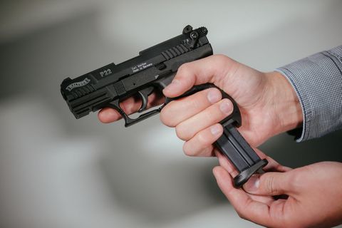 Hände laden eine Schreckschuss-Pistole "Walther P22" mit einem Magazin
