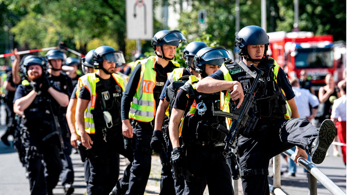 Schwer bewaffnete Polizeibeamte stehen an einem Kaufhaus am Hermannplatz
