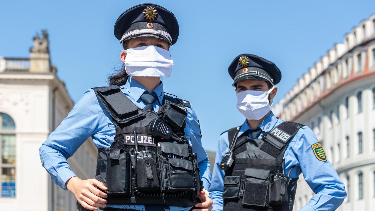 21.04.2020, Sachsen, Dresden: Polizisten stehen auf dem Neumarkt im Rahmen eines Pressetermins und tragen dabei Mundschutz. Nach einem Monat weitgehenden Stillstands wegen der Eindämmung des Coronavirus in Deutschland werden am heutigen Montag die erste... Zwei Polizisten