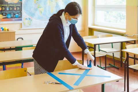 Eine Lehrerin klebt Tische ab