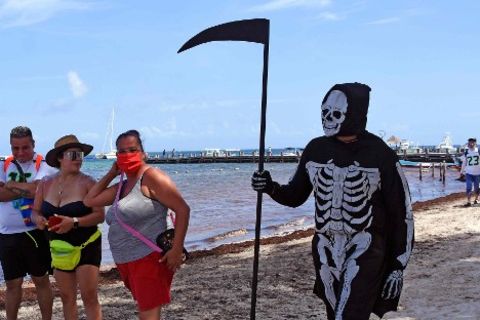 Mann verkleidet sich als Sensenmann am Strand