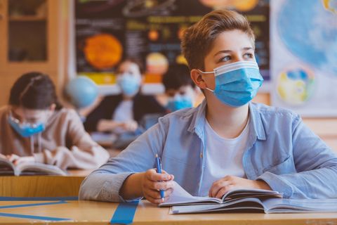 Kinder sitzen mit Mund-Nasen-Schutz im Unterricht