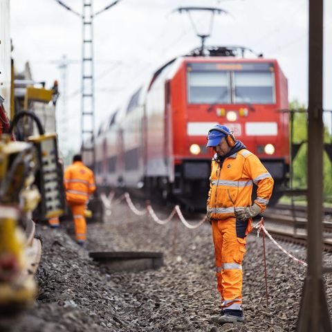 Gleisbauarbeiter sanieren eine Strecke, während nebenan der Betrieb weiter läuft