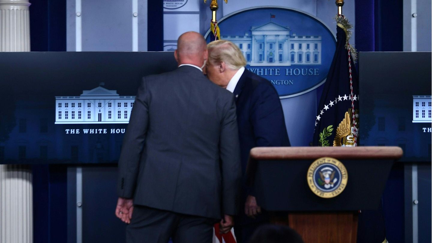 Ein Mitarbeiter des Geheimdienstes holt Donald Trump aus dem Briefing. Kurz danach kehrte der US-Präsident zu den Journalisten zurück.