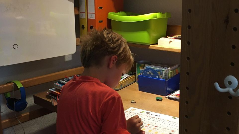 Leseraufruf: Der siebenjährige Peter lernt an einem kleinen Schreibtisch, der unter seinem Hochbett steht Der siebenjährige Peter lernt an einem kleinen Schreibtisch, der unter seinem Hochbett steht