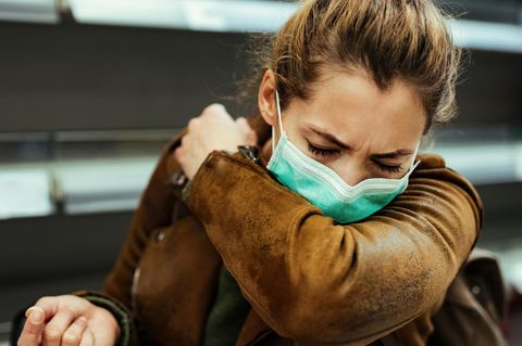 Coronavirus asymptomatische Infektion: Eine Frau hustet in den Ellenbogen