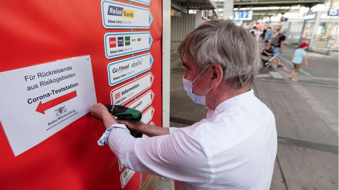 Ein Mitarbeiter des Sozialministeriums bringt im Hauptbahnhof Stuttgart Wegweiser zu einer Covid-19-Teststation für Rückreisende aus Risikogebieten an