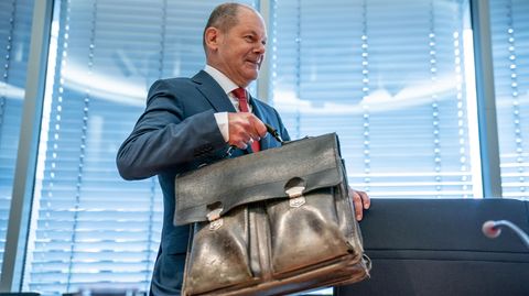 Olaf Scholz trägt eine Aktentasche
