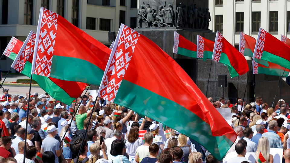 Belarus, Minsk: Hunderte Anhänger von Präsident Lukaschenko versammeln sich zu einer Kundgebung auf dem Unabhängigkeitsplatz. Sie schwingen dir rot-grüne Nationalflagge. 