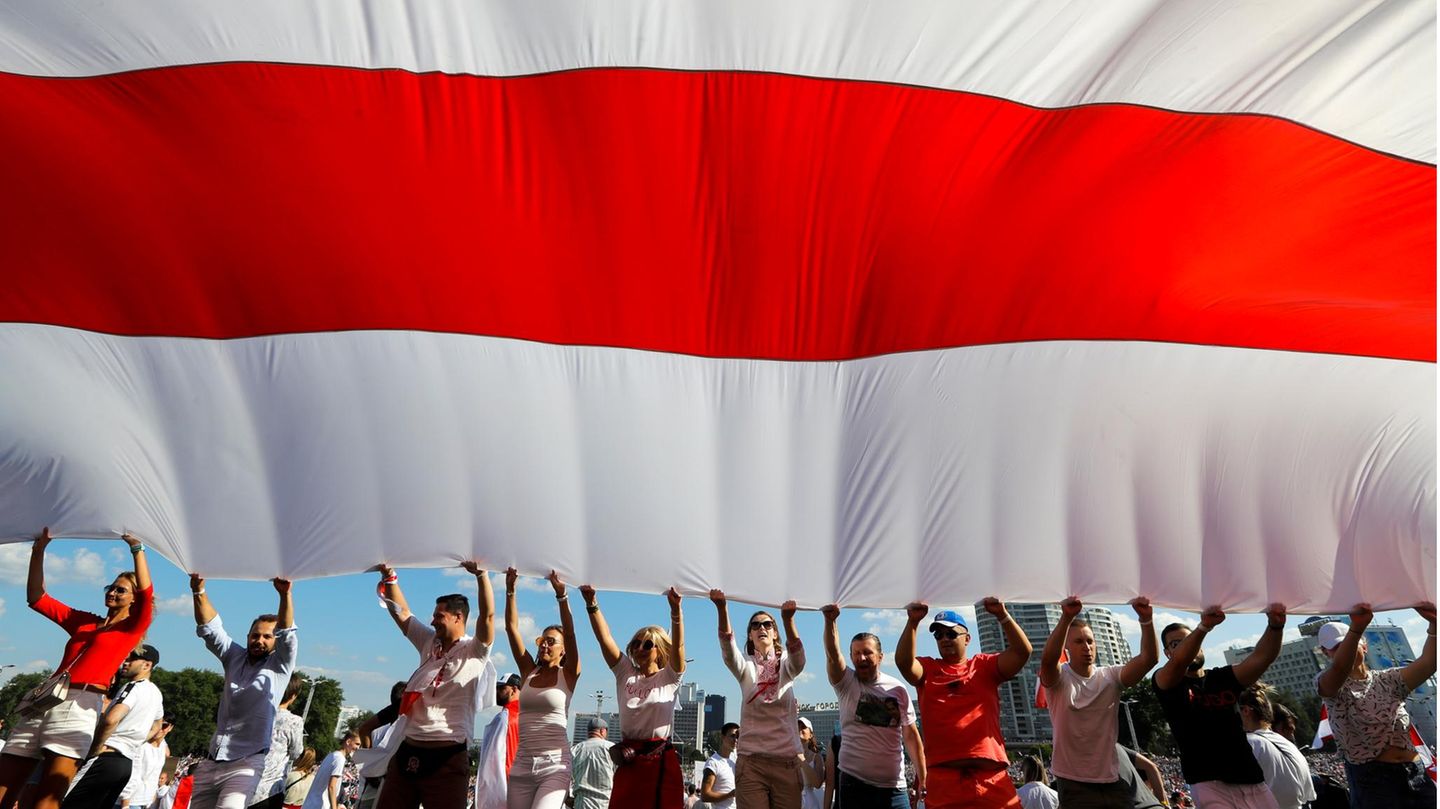 Belarus, Minsk. Anhänger der belarussischen Opposition halten eine riesige weiß-rot-weiße Flagge