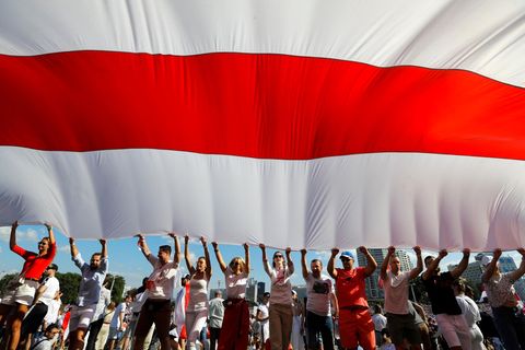 Belarus, Minsk. Anhänger der belarussischen Opposition halten eine riesige weiß-rot-weiße Flagge