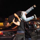 Ein Mann wird von einem anderen vor einem BMW in die Luft gehoben