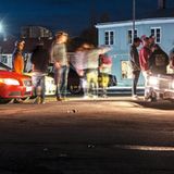 Zwei Autos leuchten eine Gruppe von Menschen an