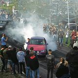 Autofahrer lassen, umring von Autofans, ihre Reifen durchdrehen