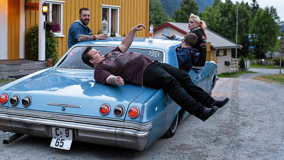 Ein Mann liegt quer auf einem Chevrolet