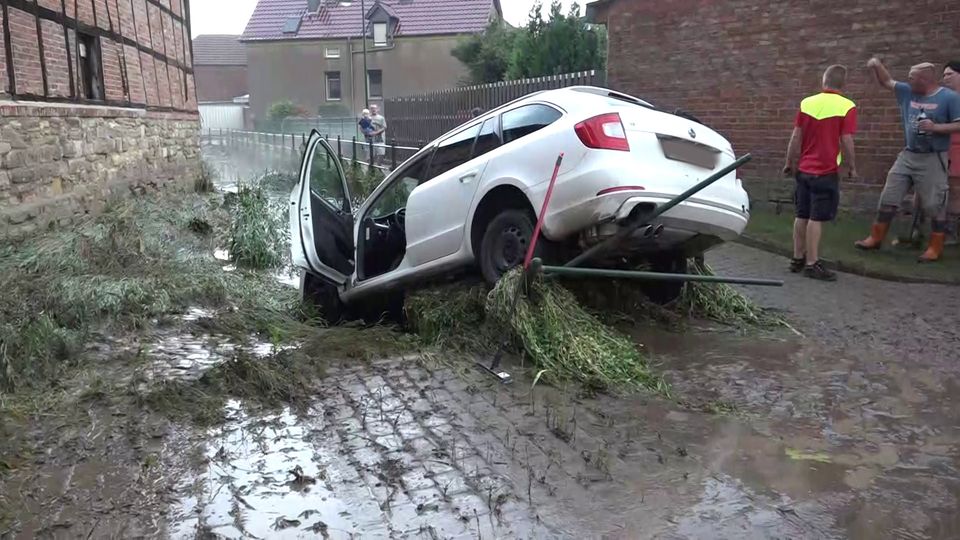 Nachrichten Deutschland Oschersleben Ein Auto, das von den Wassermassen mitgerissen wurde, hängt in einem Bachbett.