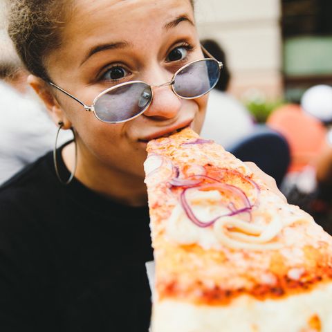 Eine Frau beißt in ein Pizzastück