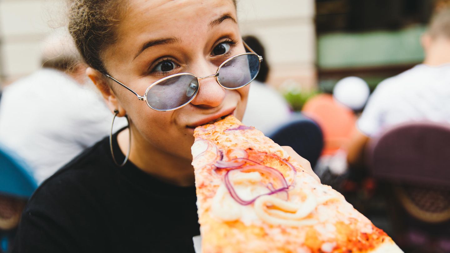 Eine Frau beißt in ein Pizzastück