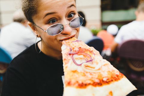 Eine Frau beißt in ein Pizzastück