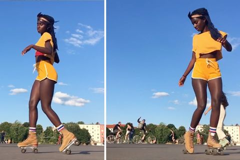 Eine schwarze junge Frau in gelbem T-Shirt und Shorts tanzt auf Rollschuhen
