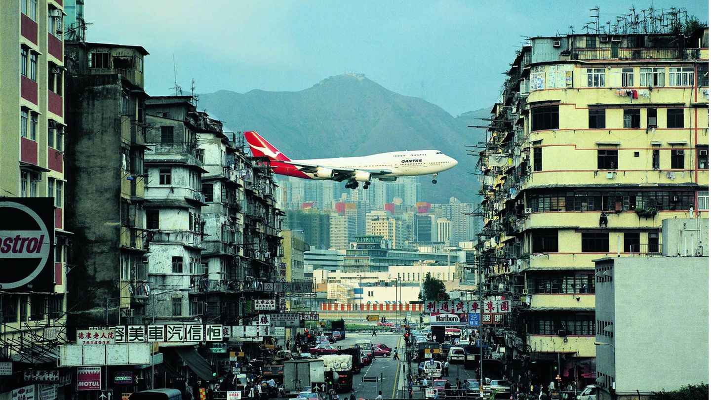 Kai Tak Airport in Hongkong  Der 1998 geschlossene Hongkonger Flughafen Kai Tak war definitiv eine Reise wert – für Dietmar Plath mehr als zehnmal. Mitten in der Millionenmetropole gelegen, stellte er eine Herausforderung für die Piloten dar, die über das Häusermeer anfliegen und erst im letzten Augenblick auf die einzige Landebahn einkurven mussten. Fast ohne Vorwarnung erschienen die Jets – hier eine Boeing 747-400 der australischen Qantas – fast zum Greifen nahe über den Köpfen der Spaziergänger in den Straßenschluchten. Ein Spektakel für die Touristen, während die an solche Anblicke längst gewöhnten Einwohner kaum noch den Kopf hoben.