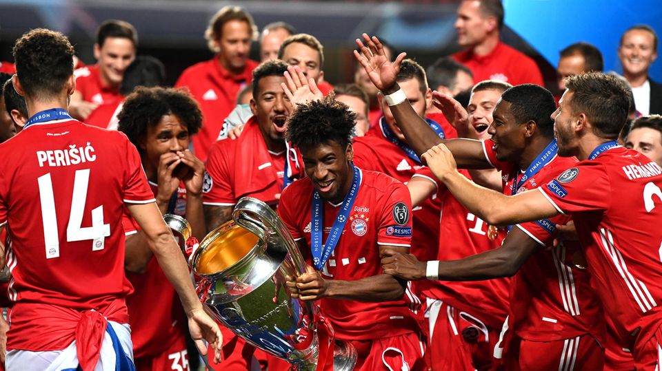 Kingsley Coman (M.) von Bayern München hält die Champions League-Trophäe und feiert mit seinen Teamkollegen den Sieg gegen Paris Saint-Germain im Estadio da Luz
