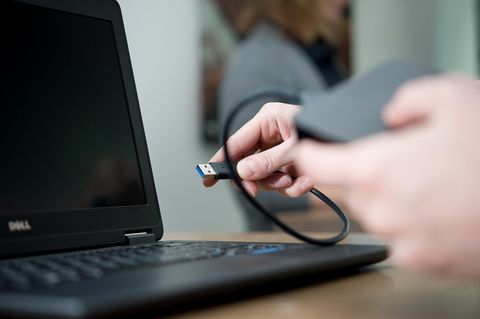 Festplatte formatieren: Frau schließt externe Festplatte an Laptop an