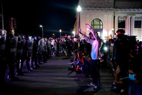 Demonstranten stehen teils mit erhobenen Armen einer Reihe Polizisten in voller Kampfmontur gegenüber