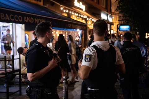 Ein Polizeibeamter und ein Mitarbeiter des Ordnungsamtes stehen vor einem Lokal in Berlin