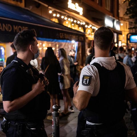 Ein Polizeibeamter und ein Mitarbeiter des Ordnungsamtes stehen vor einem Lokal in Berlin