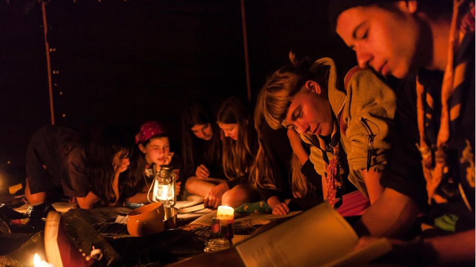 Pfadfinder sitzen um ein Lagerfeuer
